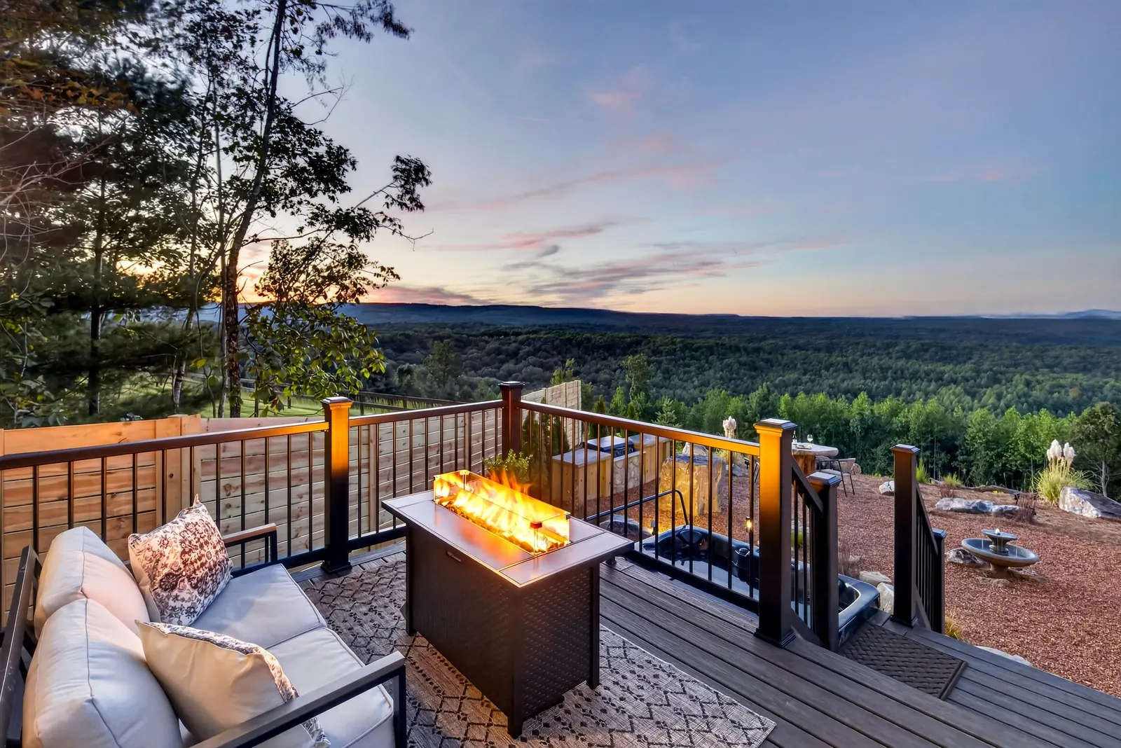 The deck's fire table glowing at dusk above the valley