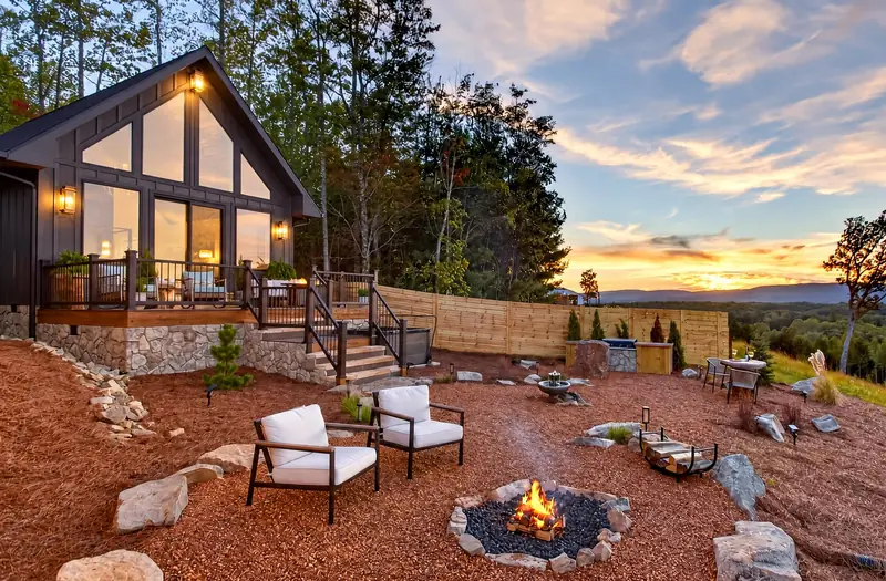 Lounge chairs gathered around the stone fire pit at dusk