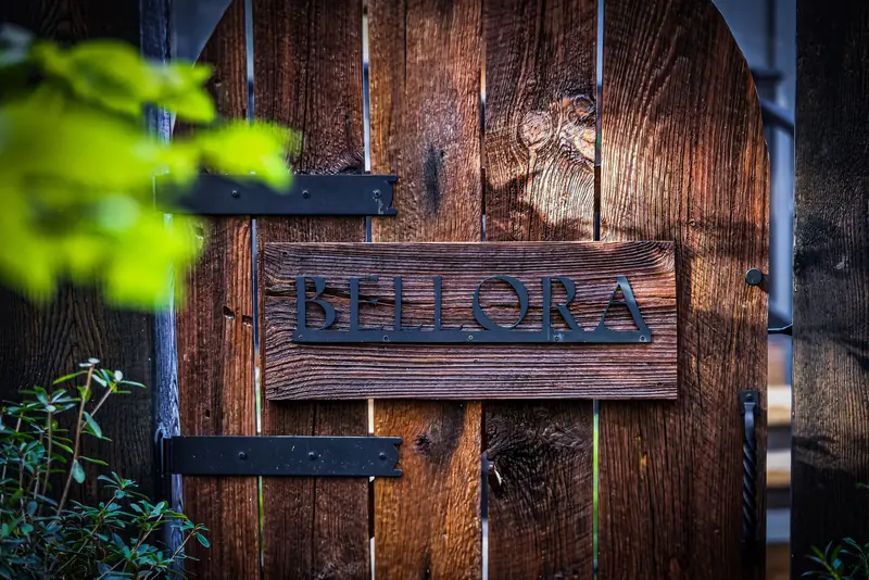 The weathered wooden gate bearing the Bellora name