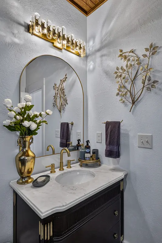 The arched vanity mirror, brass fixtures and fresh flowers