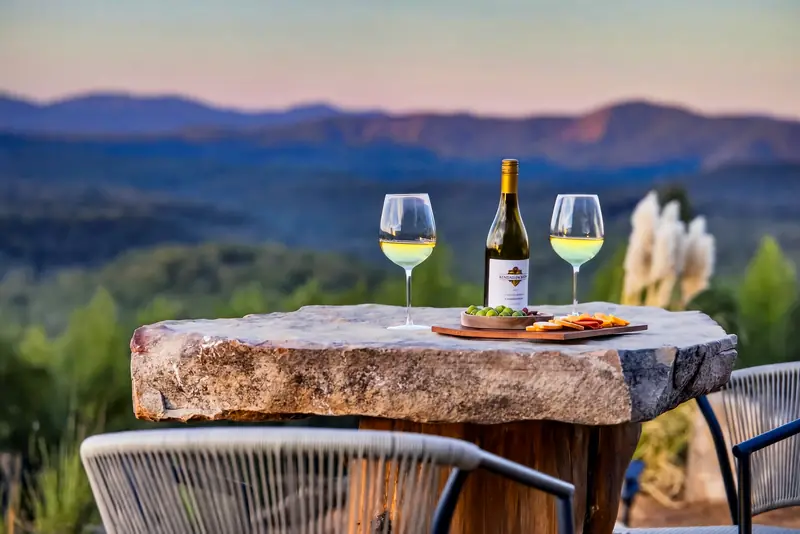 Wine for two on a stone table above the blue ridgelines